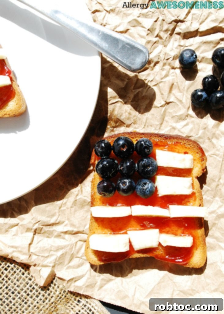 Red, White & Blue Allergy-Friendly Toast 3 A close-up of a single slice of Patriotic Toast, showcasing the detailed arrangement of blueberries, banana slices, and strawberry jam to form the American flag. This inviting breakfast is guaranteed gluten-free, dairy-free, egg-free, soy-free, peanut-free, and tree nut-free, catering to strict dietary needs.