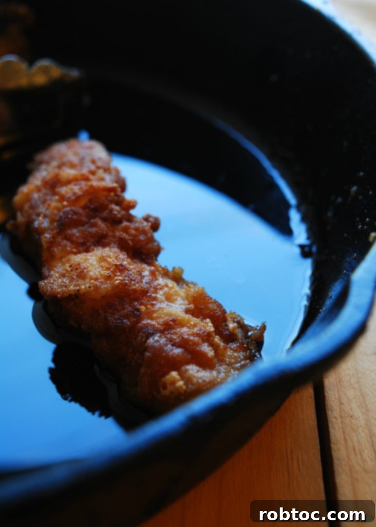 Perfectly fried chicken tenders, golden and crispy, on a wire rack after frying. A gluten, dairy, egg, soy, peanut, and tree nut-free recipe.