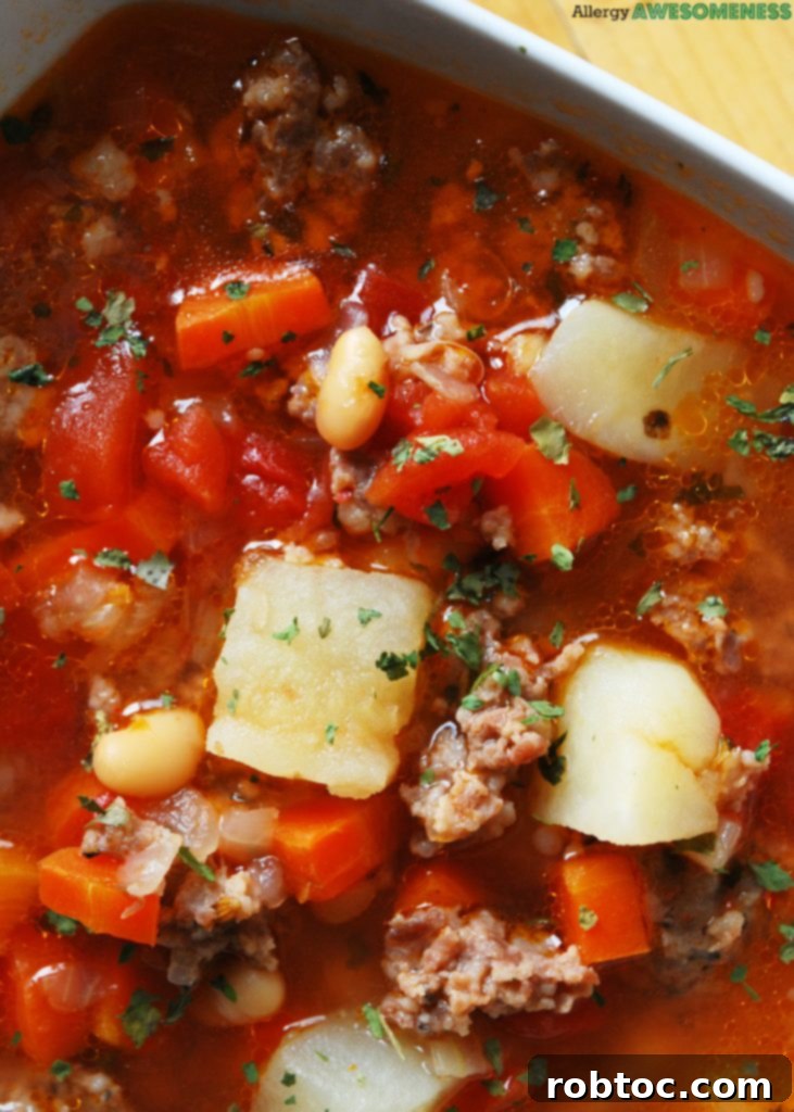 Close-up of a serving of allergy-friendly Potato & Sausage Soup with fresh ingredients.