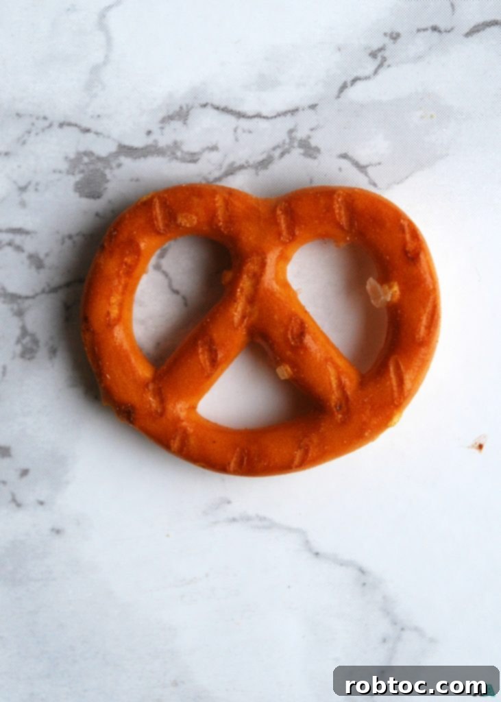 Top Allergen-Free Vegan No-Bake Chocolate Pretzel Bites 4 Step 1: Spreading SunButter on a gluten-free pretzel for the base of the no-bake treat.