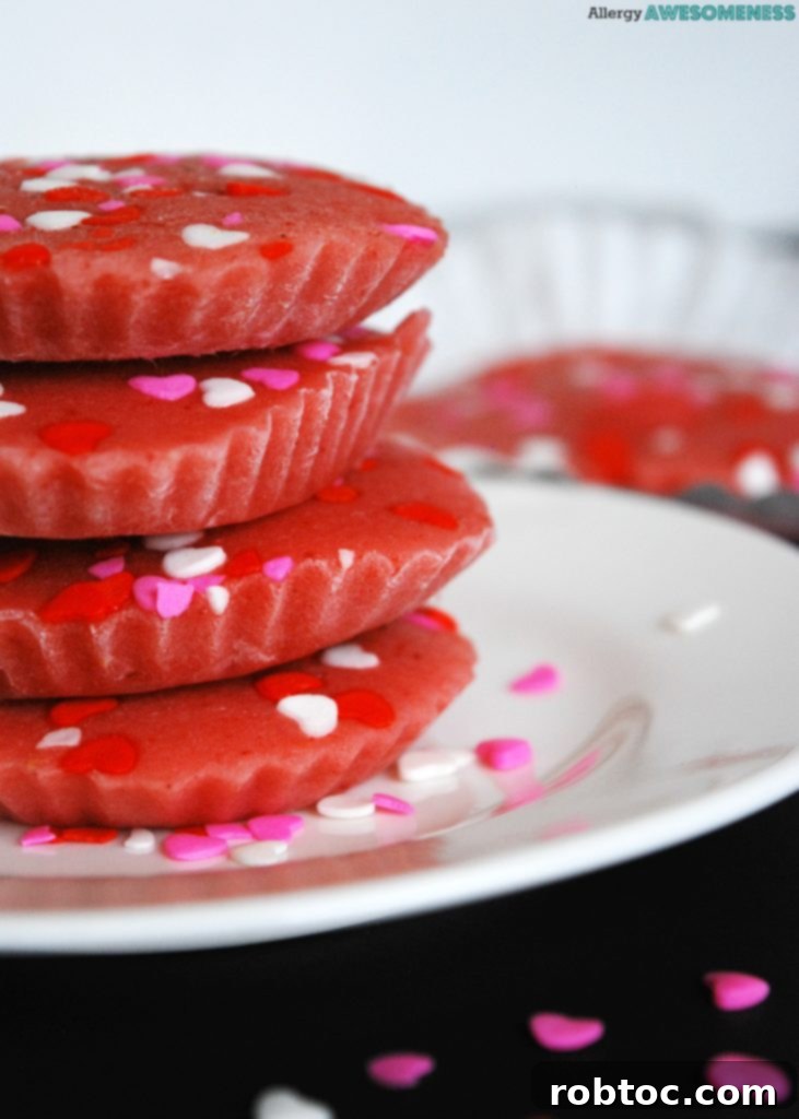 Several dairy-free frozen strawberry yogurt bites in pink silicone baking cups arranged on a baking sheet, ready for freezing