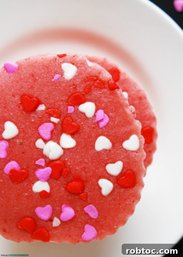 An overhead shot of dairy-free frozen strawberry yogurt bites in pink baking cups on a baking sheet, highlighting their vibrant color and readiness