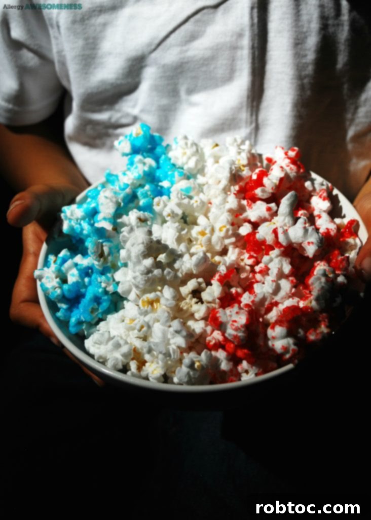 Red White and Blue Popcorn: 3 Easy Ingredients, Allergy Safe 7 Close-up of a child's hand reaching into a bowl of Easy 4th of July Treat popcorn, highlighting its irresistible appeal to kids.