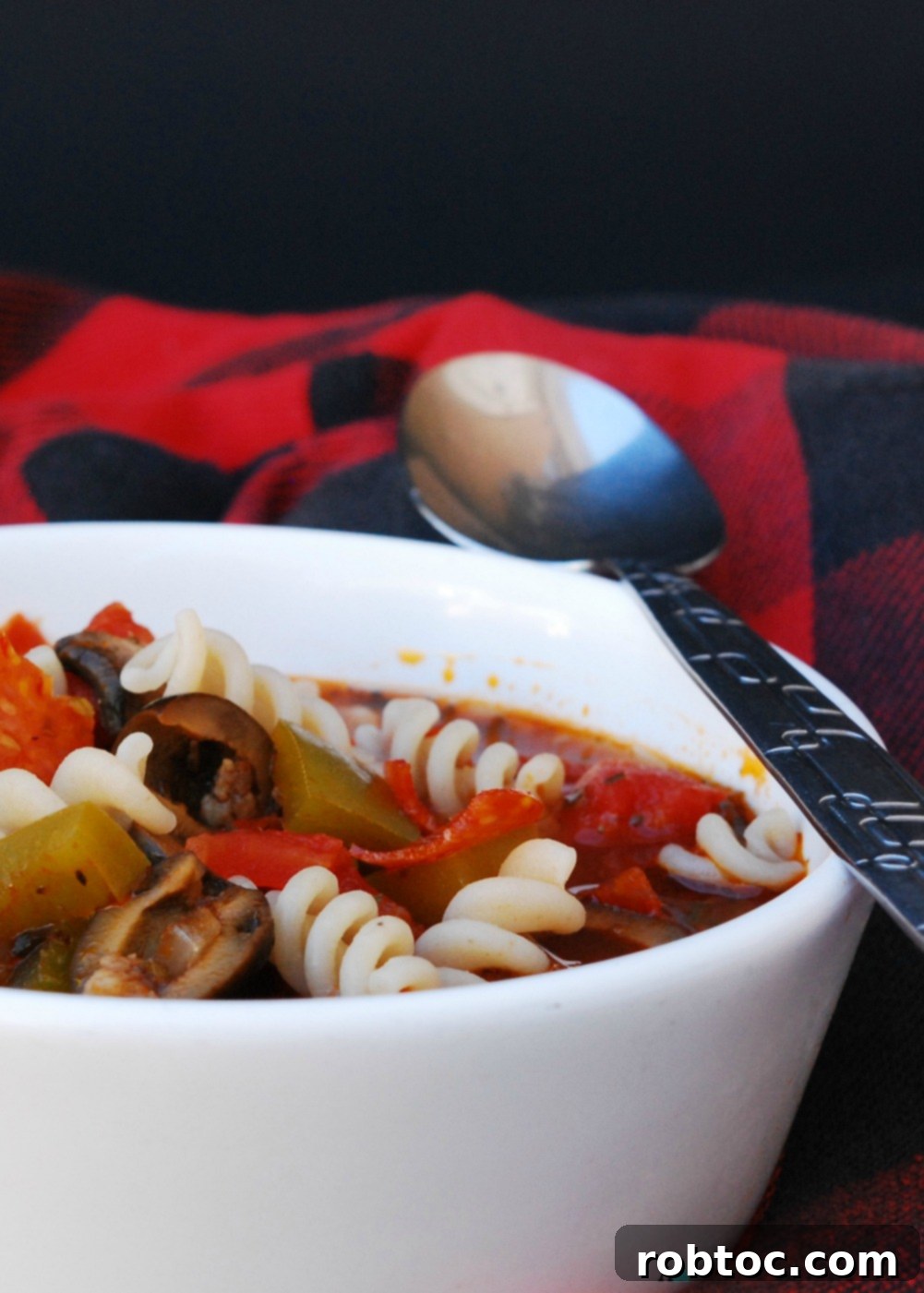 Slow Cooker Pizza Soup with a spoon, ready to serve
