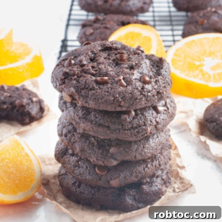 Gluten-free, dairy-free chocolate orange cookies stacked with orange slices