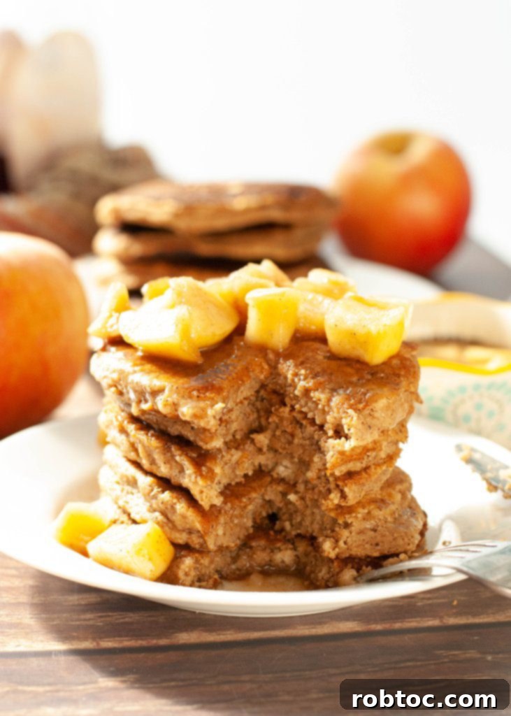 A comforting breakfast scene with a plate of applesauce pancakes, topped with golden sautéed apples and a hint of cinnamon.