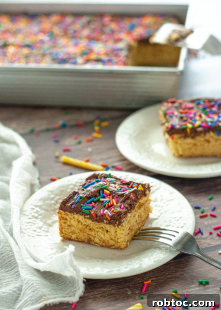 Two slices of vegan gluten-free yellow cake with chocolate frosting sitting next to the baking pan.
