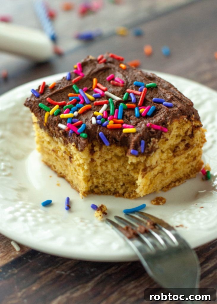A slice of gluten-free vegan yellow cake with a bite taken out, showing the moist texture, next to the pan.
