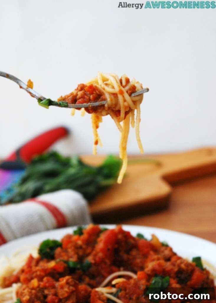 Slow Cooker Bolognese: Made for Everyone 3 Closeup of a fork twirling gluten-free spaghetti coated in rich slow cooker bolognese.