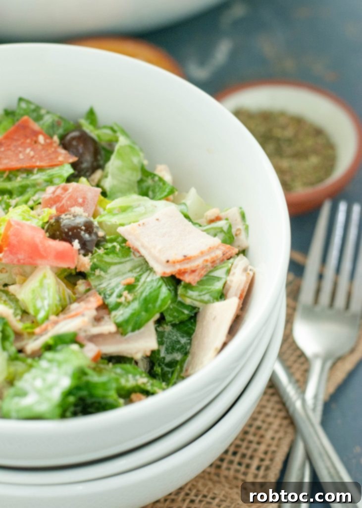 Ultimate Gluten-Free Dairy-Free Italian Grinder Salad 75 close-up view of a vibrant Italian chopped salad in a white bowl, showcasing colorful ingredients like pepperoni, olives, and greens