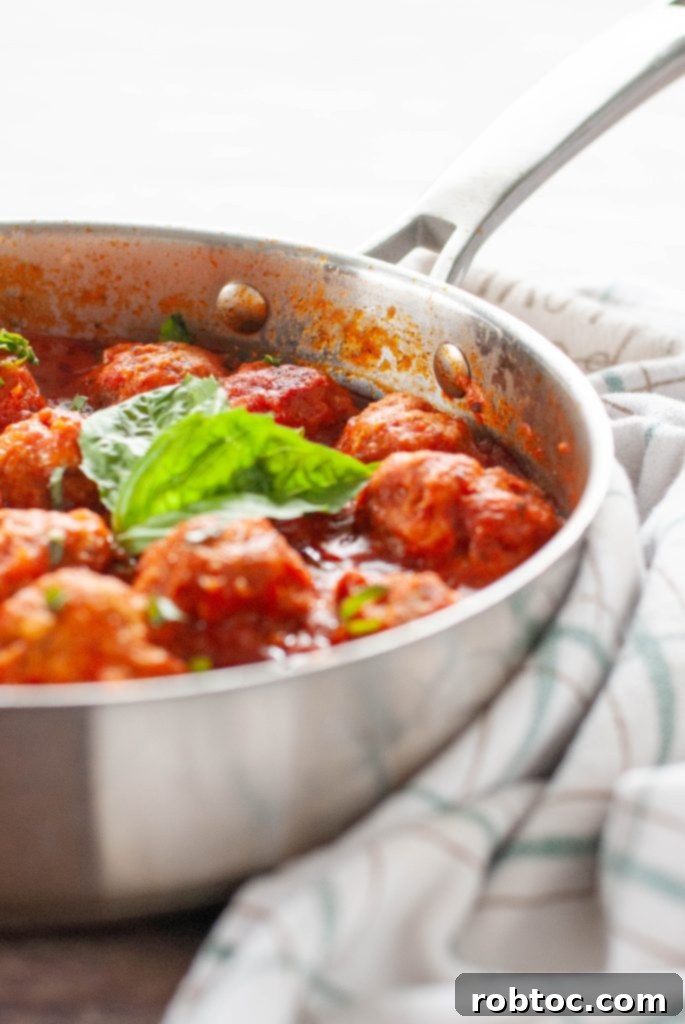 Gluten-free meatballs simmering in marinara sauce in a stainless steel skillet, ready to serve
