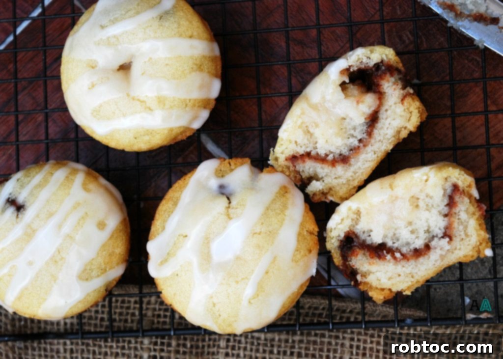 Plant-Based Gluten-Free Cinnamon Swirl Muffins 4 Three golden brown Cinna-Swirl Muffins with sweet glaze on a cooling rack.