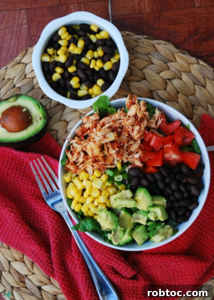 A vibrant, fully textured slow cooker salsa chicken salad bowl, featuring succulent shredded chicken, fresh lettuce, corn, black beans, avocado, and tomatoes, all gluten-free and top 8 allergen-free.