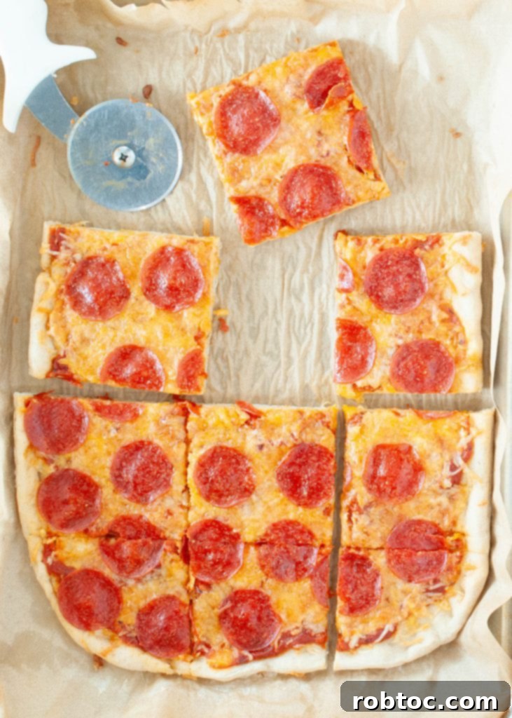 Chewy gluten-free pizza crust recipe shaped into a rectangle, shown from above with a slice missing, highlighting its fluffy texture