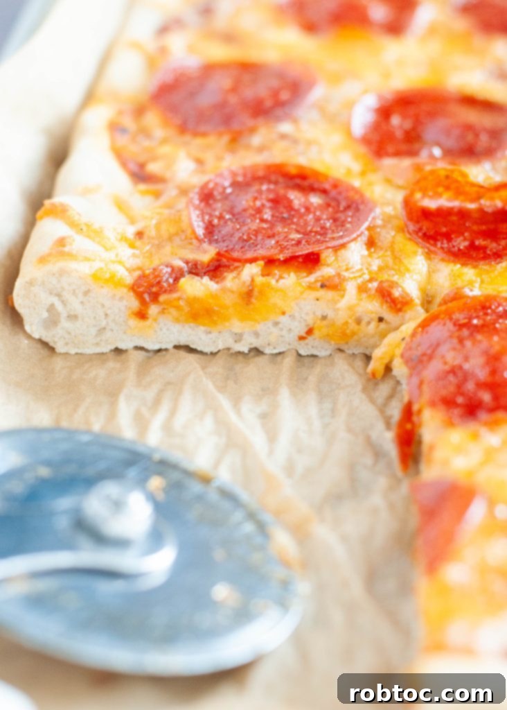 Soft gluten-free pizza crust recipe shown with a slice gone from an angle, showcasing its fluffy interior