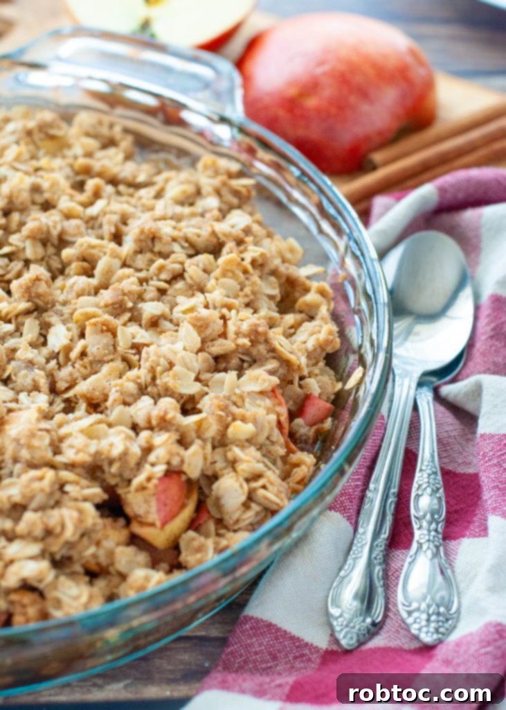 Quick and Easy Gluten Free Apple Crisp 3 A close-up shot of a warm, golden-brown gluten-free apple crisp baked in a clear glass pie plate, showcasing the rich texture of the topping and bubbly apple filling.