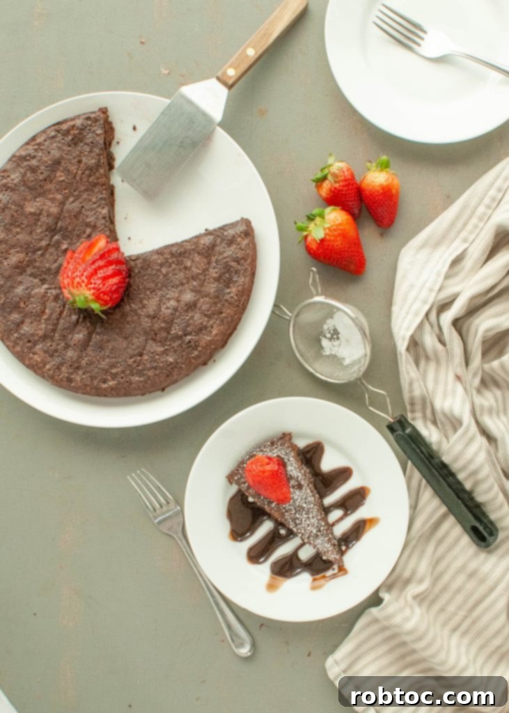 flourless-chocolate-torte-with-one-slice-on-a-plate-rest-of-cake-in-the-pan-shot-from-above-with-strawberries