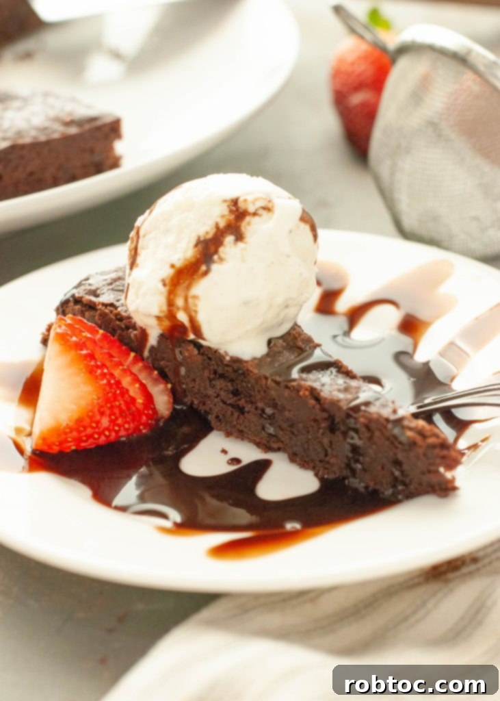 flourless-chocolate-torte-slice-side-angle-with-chocolate-sauce-and-vanilla-ice-cream-on-top