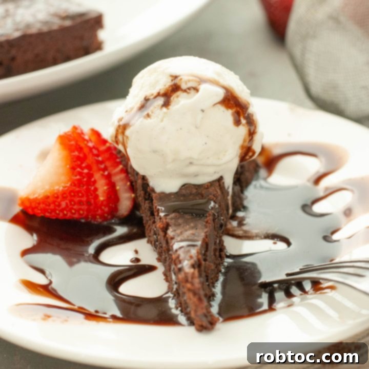 flourless-chocolate-torte-with-ice-cream-and-chocolate-sauce-on-top-with-a-strawberry-next-to-it-straight-on