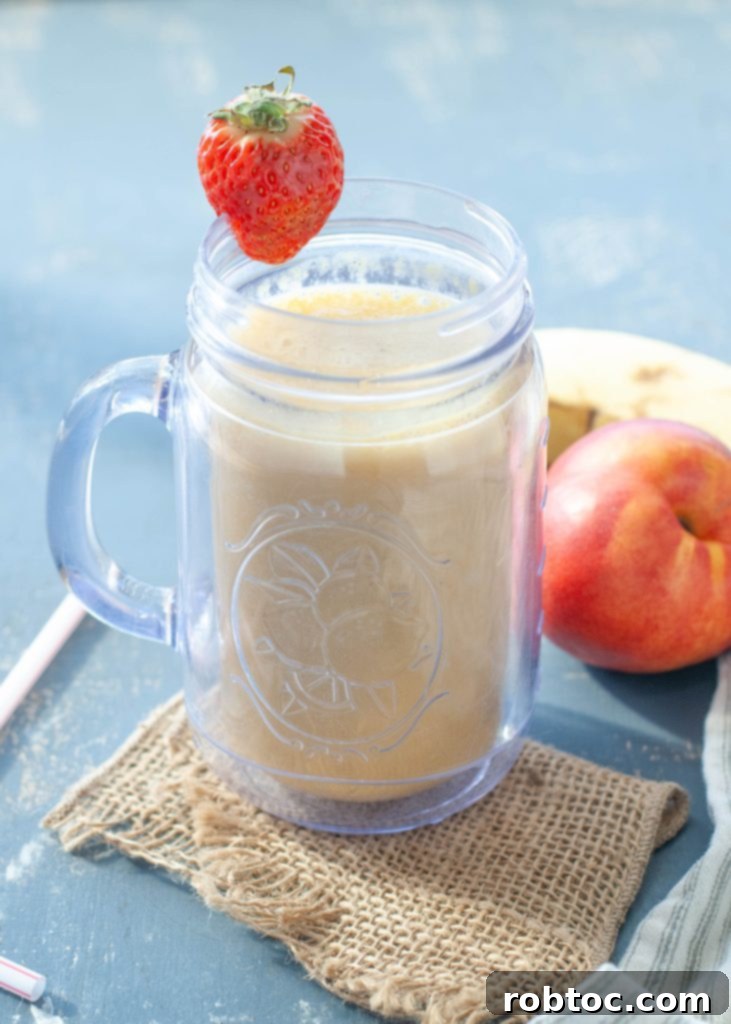 Close-up of a vibrant dairy-free peach protein smoothie garnished with a fresh strawberry on the rim, appealing and refreshing.