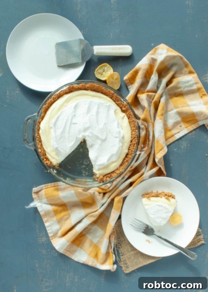 A whole gluten-free dairy-free lemon cream pie with one slice removed, elegantly presented on a white plate, ready to be served.